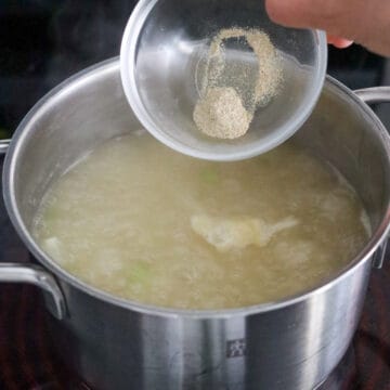 Seasonings being added to the thickened soup in the pot.