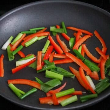 Next heat vegetable oil in a large pan on medium heat. Fry chopped green onions and red bell pepper for 1 minute until softened.