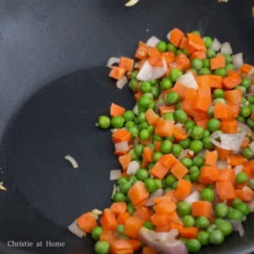 Add 1 teaspoon / 5 ml of vegetable oil into the pan. Sauté garlic and shallots for 10 seconds. Add peas and carrots and fry for 10 seconds. Push everything to the side of the pan.