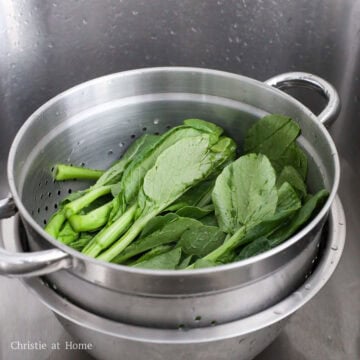 Rinse the trimmed yu choy under cold running water until it runs clear. Wash between the leaves to remove dirt or insects. Then strain out the water.