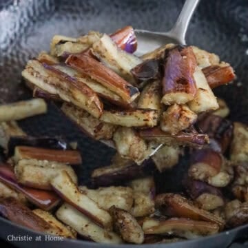 Coated eggplant pieces frying in oil in a pan until tender and lightly browned.