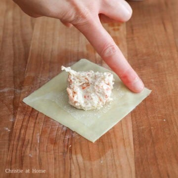 Prepare a small bowl of cold water nearby. On a clean working surface, lay flat one wonton wrapper and add 2 teaspoons of the filling into the center (avoid overfilling). Lightly dab water along the edges of the wrapper.