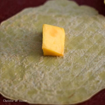On a clean working surface, place the pancake yellow-side down and the fried-side up and place one piece of mango in the center.