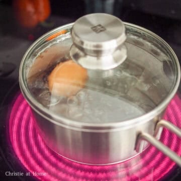 Eggs boiling in water, then transferred to an ice bath before being peeled and sliced in half.