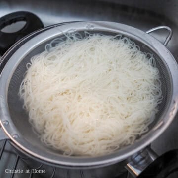 Thin noodles boiling, then rinsed under cold running water while gently rubbed to remove excess starch.