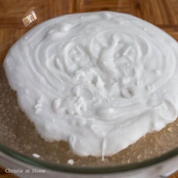 Cooked tapioca being strained through a fine-mesh sieve and rinsed under cold water, then combined with coconut milk in a large bowl.