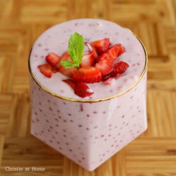 Strawberry sago pudding being portioned into bowls or glasses, topped with diced strawberries, and garnished with fresh mint.