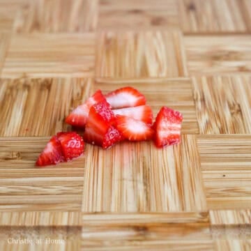 Remaining strawberries being diced into small cubes for topping.
