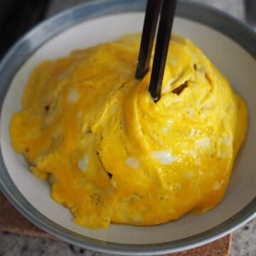 Once egg tornado is cooked, with the help of the chopsticks slide it on top of the rice. Repeat this process again with the remaining egg for the second omelette.