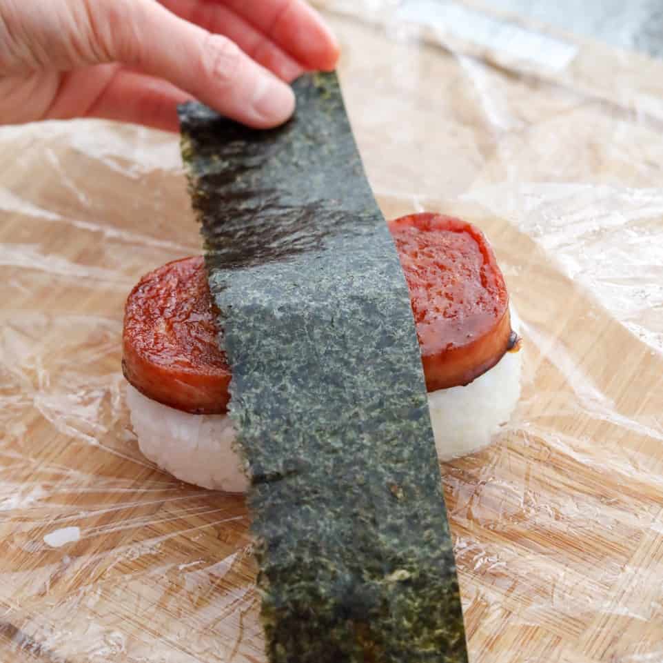 Cut your nori sheet horizontally into 5 equal sized strips with scissors. Wet your hands with a little water to prevent the rice from sticking and place sliced spam on top of rice with the shiny side up. Wrap a strip of seaweed around the whole piece. Enjoy!