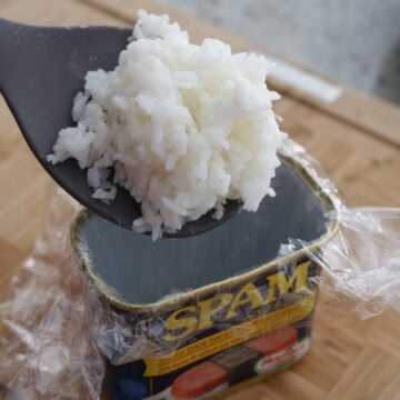 Divide seasoned rice into 5 equal portions using a wet rice paddle. Scoop 1 equal amount of rice into the bottom of the can.