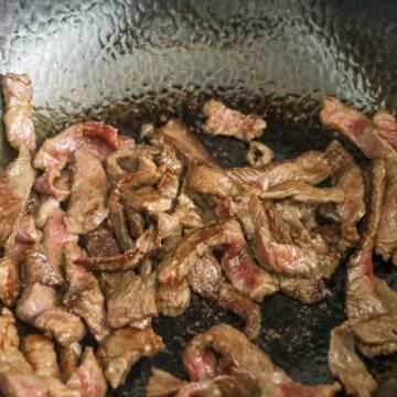 Heat a large pan over medium heat, add vegetable oil and marinated beef. Spread beef apart and fry until 80% cooked.