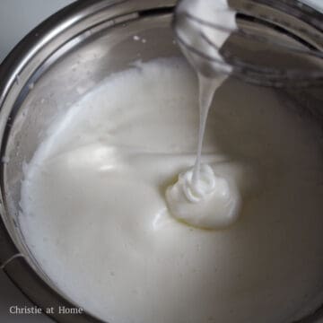 Beat egg whites with an electric hand mixer and gradually add the white granulated sugar in three equal portions. The meringue should reach a soft peak, not a stiff peak or this will cause large cracks in your cake. If you under whisk, you cake will have dents. In order to tell if it's a soft peak, stir the meringue with the whisk and lift it up. If it forms a wiggly tail at the end of your whisk that doesn't fall, the meringue is ready.