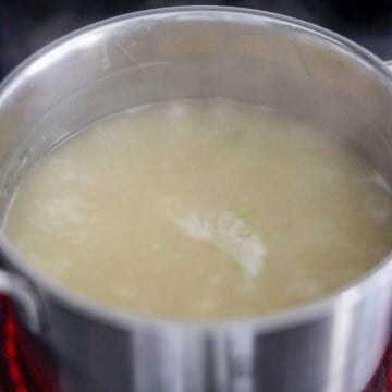 Cornstarch slurry being poured into the simmering broth while being stirred.