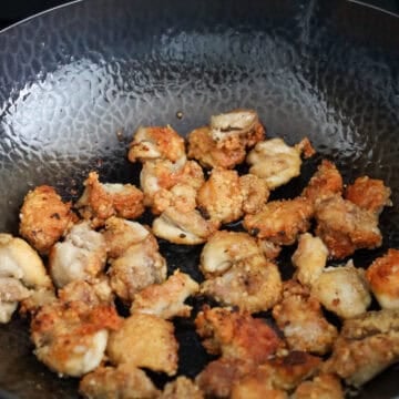 Chicken frying in a pan of hot oil over medium-high heat, turning golden and crisp in small batches.