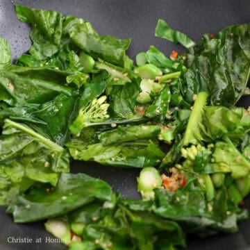 Sauté minced garlic and chopped red chilies for 10 seconds. Push to the side. Add remaining vegetable oil into empty space. Then add chopped Chinese broccoli and toss with aromatics. Cook until leaves have softened, about 1 minute.