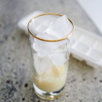Then in two separate glasses, fill them each with 1 tablespoon of condensed milk followed by divided ice cubes. If you prefer this hot, pour into a mug and skip the ice cubes.
