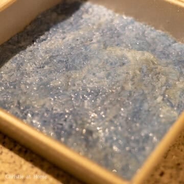 Then grease a 9x9 square baking pan or baking dish with vegetable oil. Using oven oven mitts, slide the blue rice into the greased square baking pan to create an even layer. Use a spatula to pack the rice down hard ensuring there are no holes or cracks to prevent the custard layer from seeping through them. Smooth out the layer of rice.