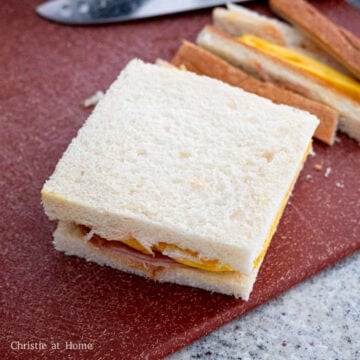 Warm up the slices of ham in the pan for only 20-30 seconds or it'll dry out. Remove and set aside. Spread butter on both slices of bread from edge to edge. Fill the sandwich with the omelet and ham. Slice the crusts off the sandwich with a serrated knife. Enjoy warm!