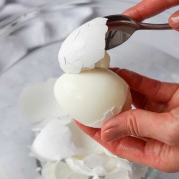 Gently peel the eggs by cracking them with the back of the spoon. Then lift the cracked egg shells with the spoon from the less pointy side.