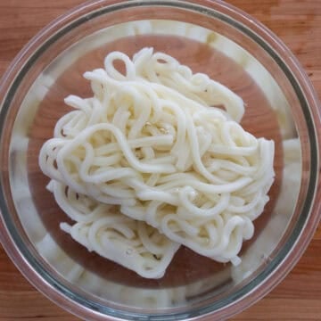 Soak frozen udon noodles in hot boiling water for 30 seconds or until loosened and strain immediately in a colander. Set aside.
