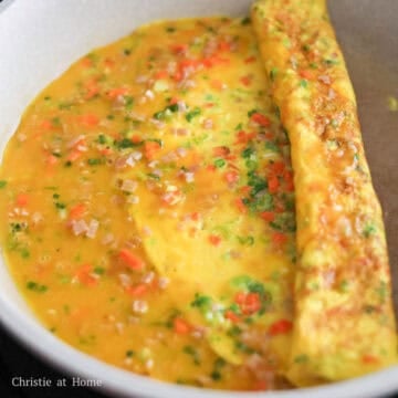 slide the omelette to the midway point of the pan and fill the open space of the pan with another thin layer of the egg mixture so it adheres to the round side and repeat the folding process