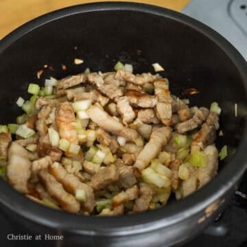 First heat a small pot or Korean earthenware clay pot on medium heat. Once hot, add sliced pork belly and fry for 2 minutes until cooked through and some of the fat renders out. Then sauté garlic, onions with the pork.