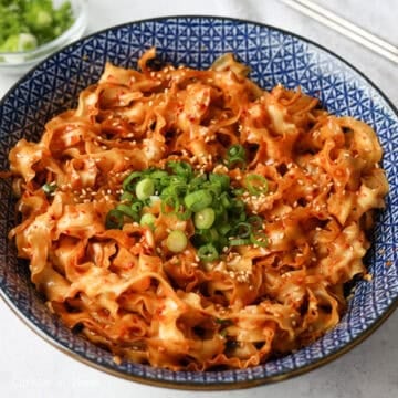 Mix the noodles with chopsticks or kitchen tweezers until they're evenly coated in the sauce. Garnish with green onions and sesame seeds and enjoy!