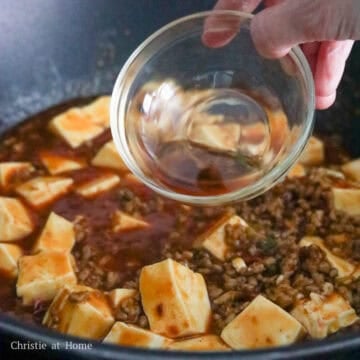 Then add in diced tofu and gently toss it with sauce using a spatula by lifting from the bottom. Next season with sesame oil and garnish with scallion greens.