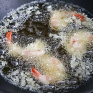 In a large heavy bottomed pan, heat vegetable oil or any neutral oil on medium high heat until you reach 350 degrees F with a digital instant read cooking thermometer. Or insert a wooden spoon into the hot oil and look for rapid bubbles. Lower battered shrimp into the hot oil away from you. Fry in small batches, about 3-4 pieces per batch.