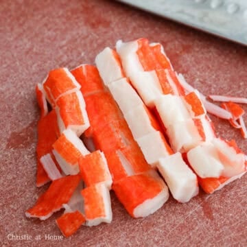 Cutting imitation crab meat into 1-inch pieces on a cutting board.
