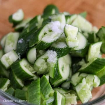 Then transfer the sliced cucumbers to a large bowl. Add the salt and gently massage it into the cucumbers. Let them sit for 5-10 minutes to draw out excess liquids, then discard the released liquid.