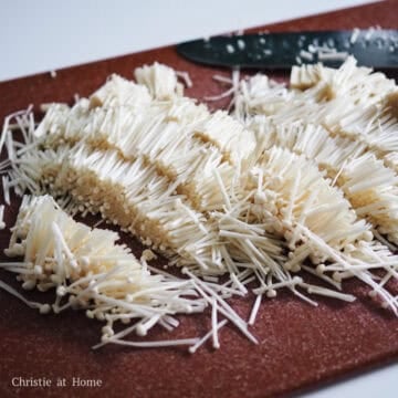 Slice enoki mushrooms into 1 inch long pieces.
