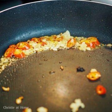 Heat vegetable oil in a large pan on medium-high heat. Sauté garlic and red chilli and avoid inhaling the red chilis as they can cause you to cough.