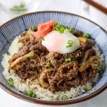 Remove the pan off heat. Serve the beef and onions over steamed rice with some of the broth. Garnish with green onions, sesame seeds, pickled ginger or an onsen tamago as desired.