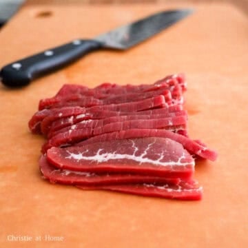 Flank steak sliced into ¼-inch strips in a large bowl, ready for marinating.