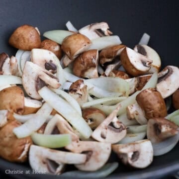 Onions and mushrooms sautéing in a pan before adding the sauce.