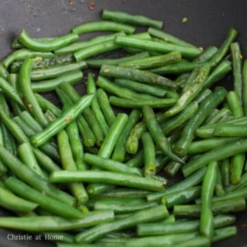 Add remaining vegetable oil into the pan followed by string beans and ⅓ cup or 80 ml of water. Toss for 10 seconds. Then cover and steam until all the water has evaporated and the string beans taste tender, about 3-4 minutes. If not tender yet, add 2 tablespoons or 30 ml of water and continue steaming until they are.